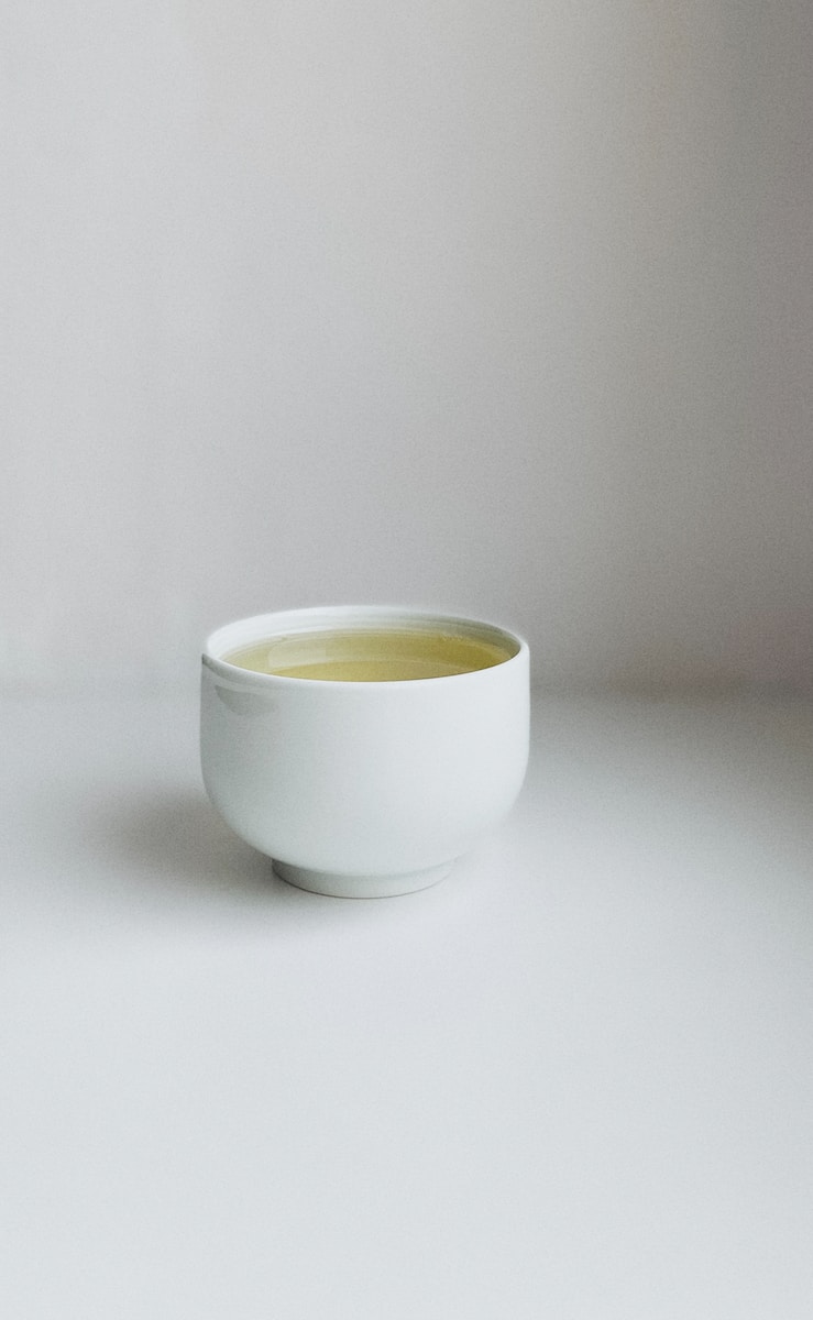 white ceramic cup on white table